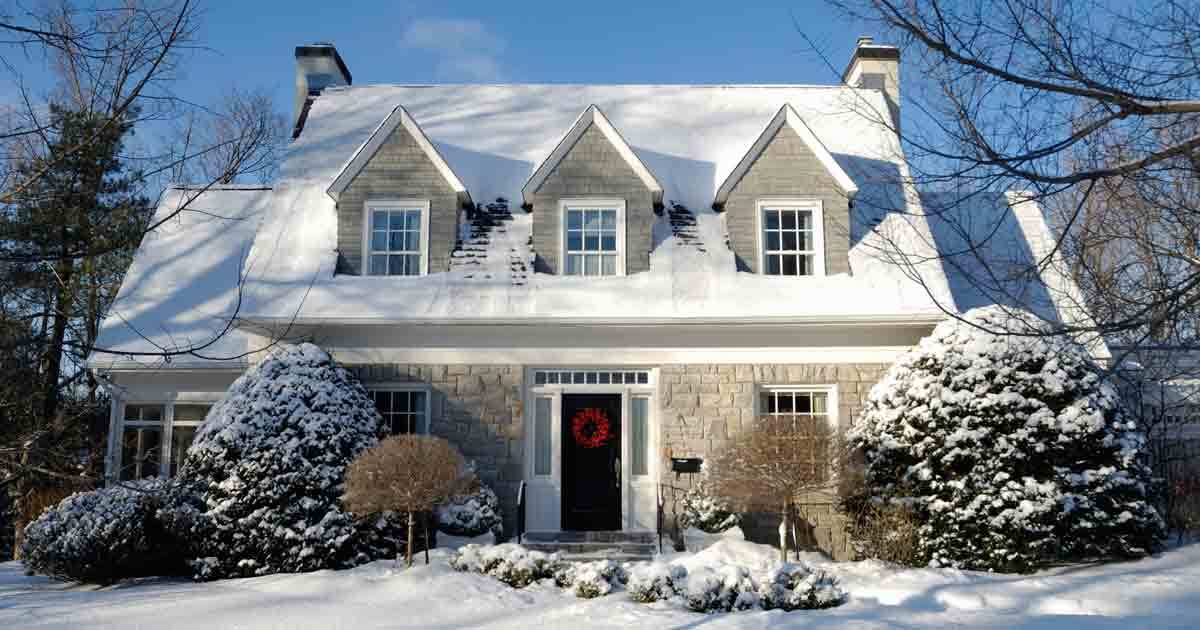 A house with multiple dormers is covered in winter snow.