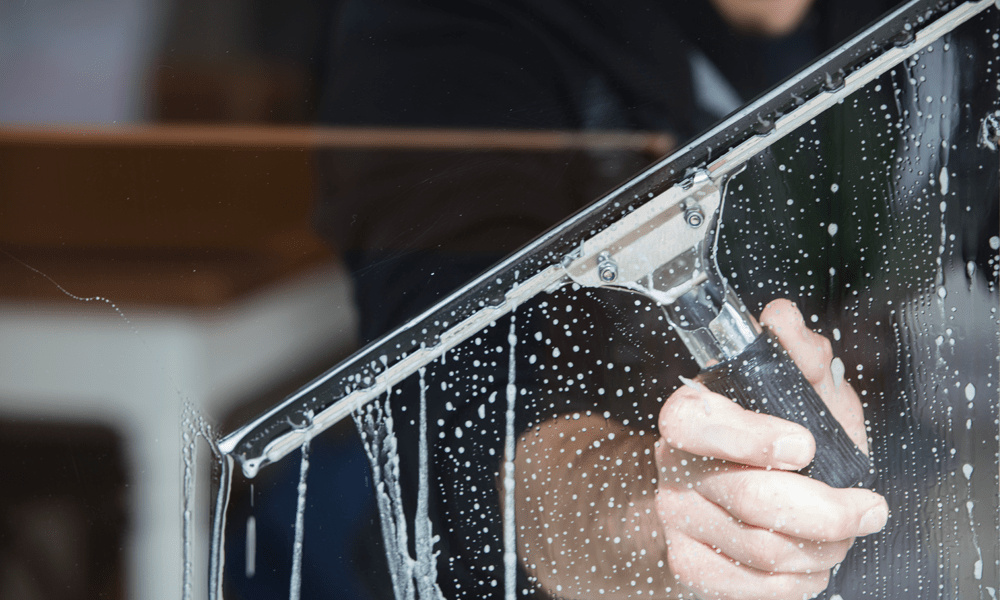 A close up of a squeegee cleaning a window.