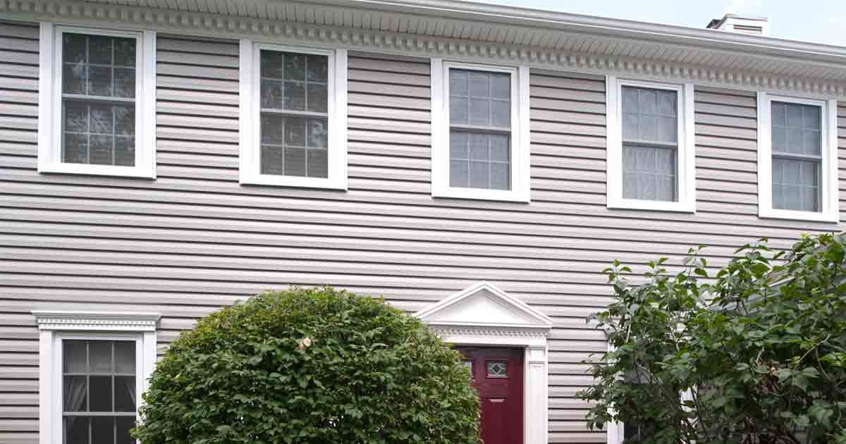 Gray siding on a house with a red front door.