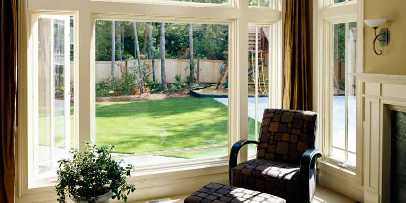 Large picture window with a view of a backyard lawn from a sitting area