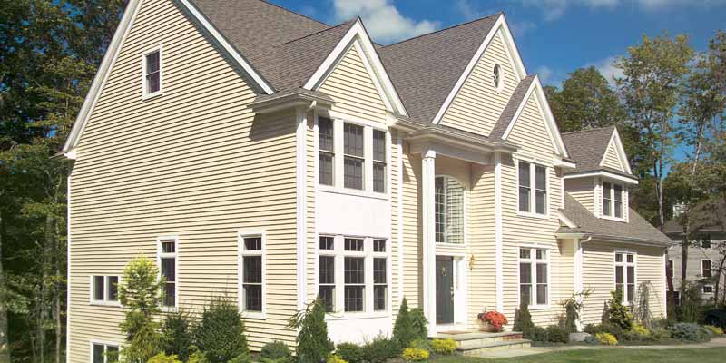 The exterior of a house with a creamy yellow siding.