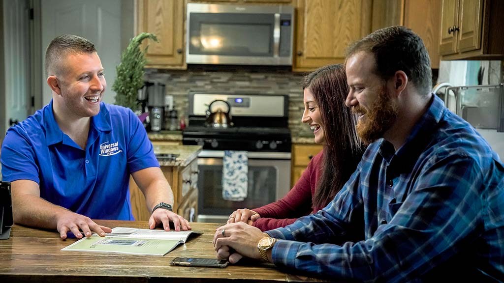 A Universal Windows Direct representative meets with homeowners at their dining table.