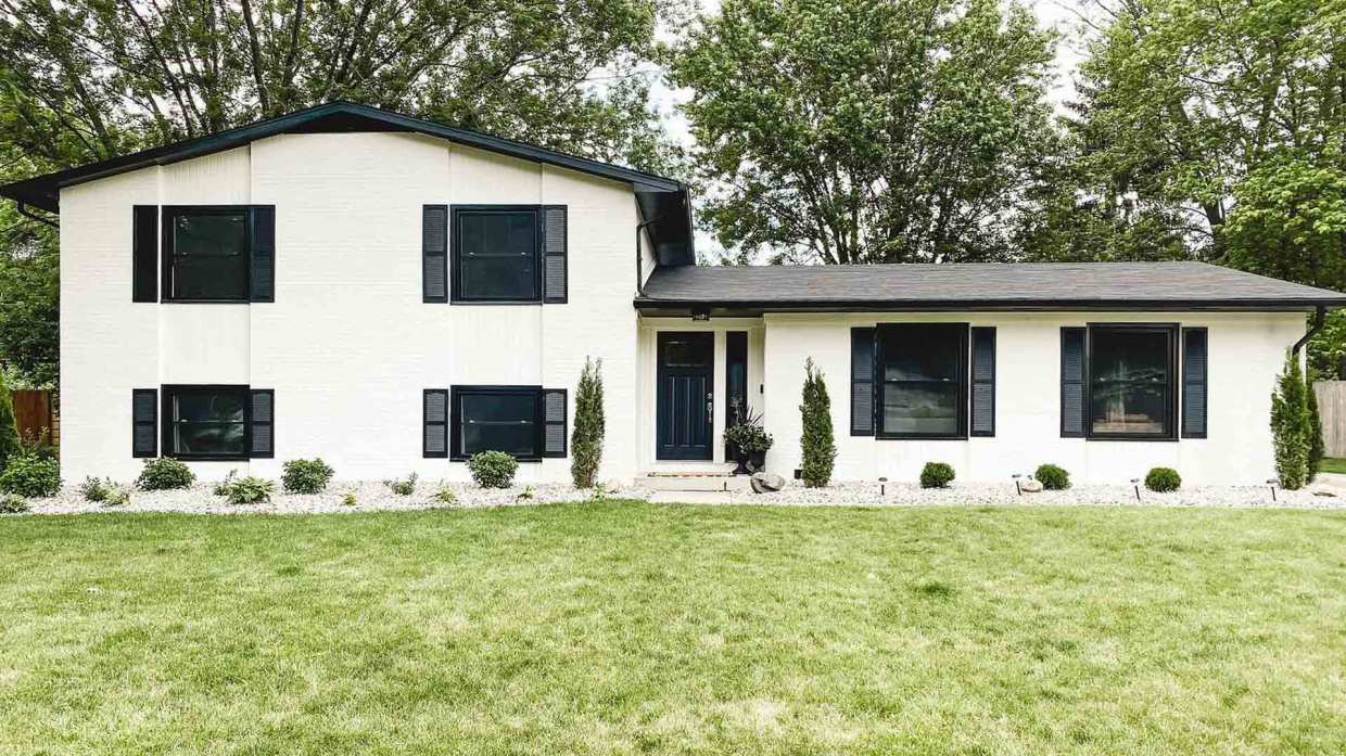 The exterior of a house with black windows and shutter.