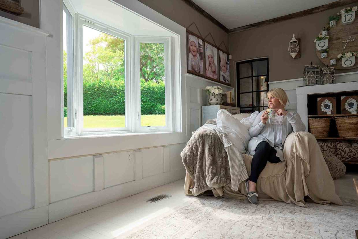 A woman gazes out her new windows installed by Universal Windows Direct.