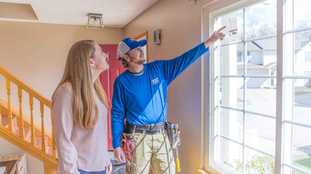 A Universal Windows Direct installer explains a new window to a homeowner.