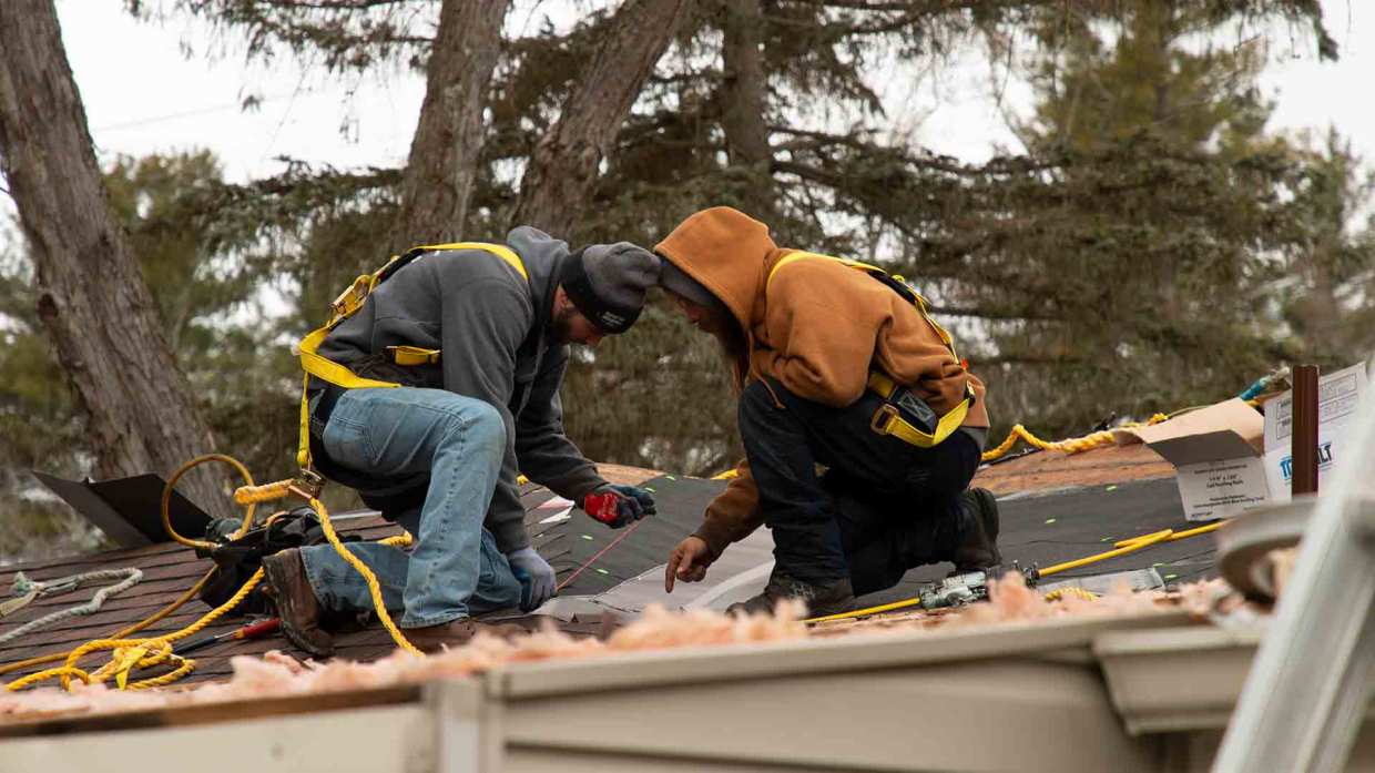A pair of Universal Windows Direct pros work on a roof installation.
