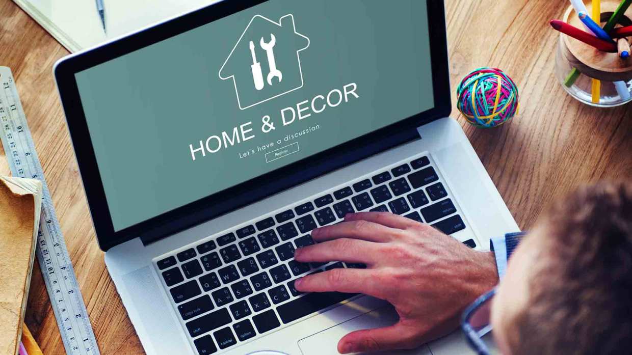 A hand rests on a laptop keyboard while the screen reads, "Home & Decor Let's have a discussion"