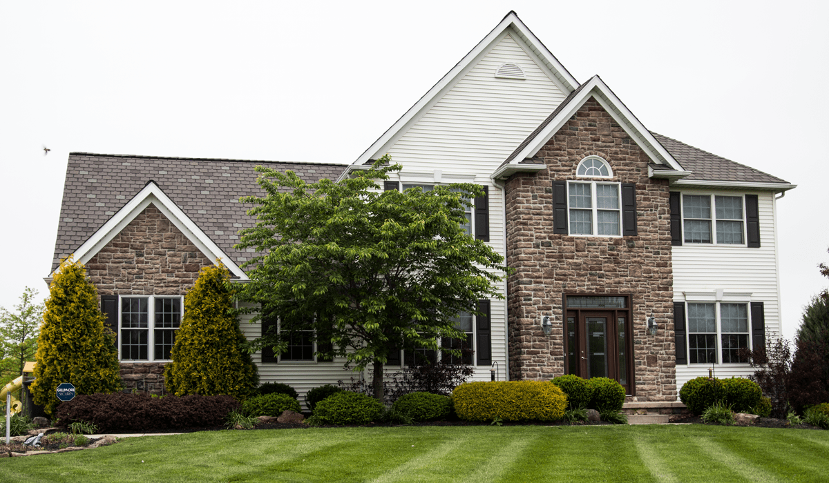 Full exterior of a house with stone and white siding.