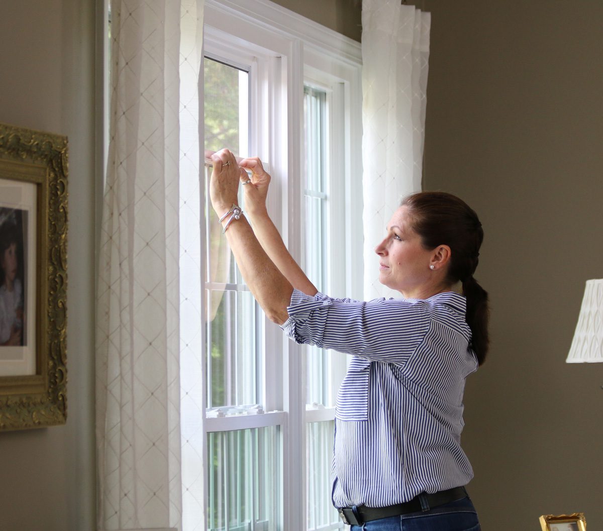 A woman closes her living room windows.
