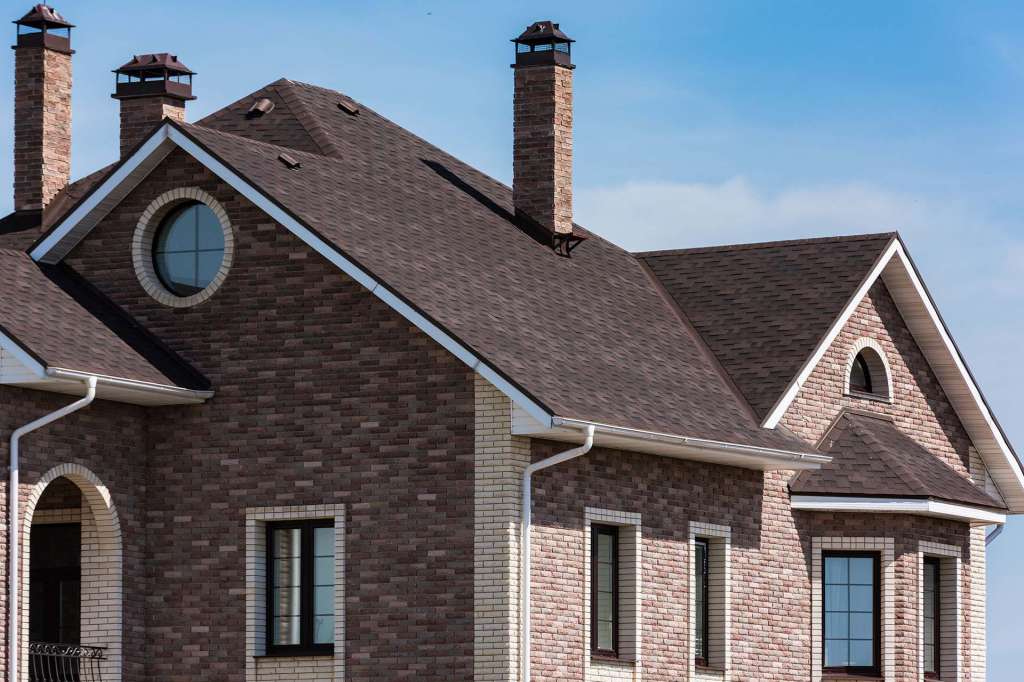 Brick home with a new dimensional shingle roof and chimneys