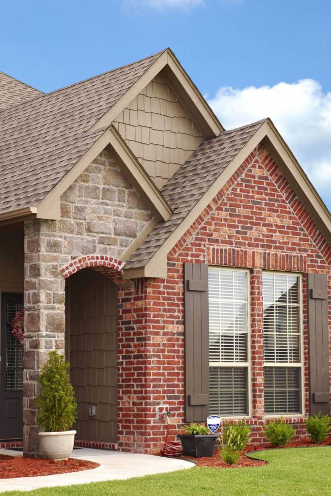Brick and stone home with new windows and dark shutters