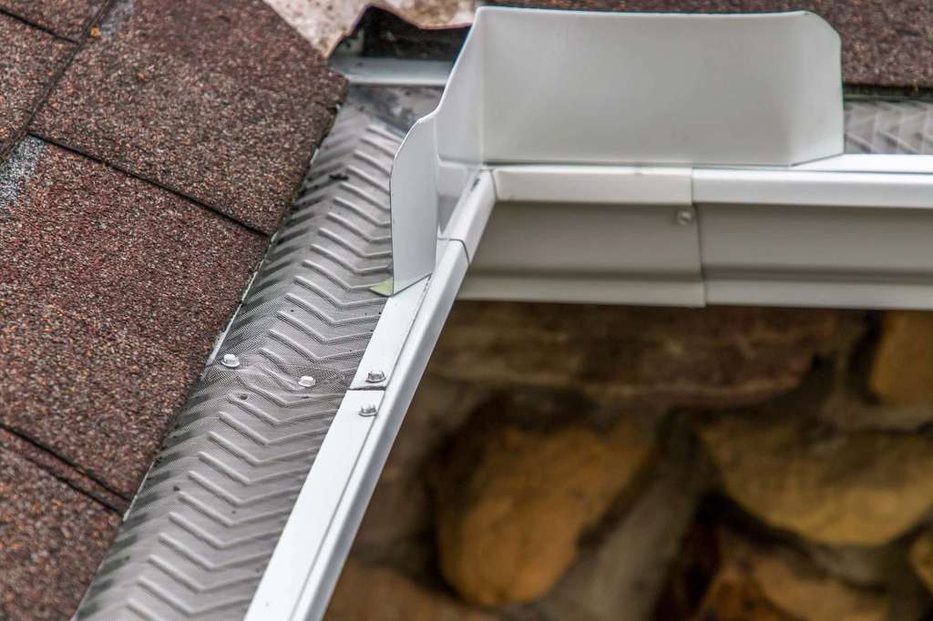 Micro-mesh gutter guard installed along a shingle roof edge