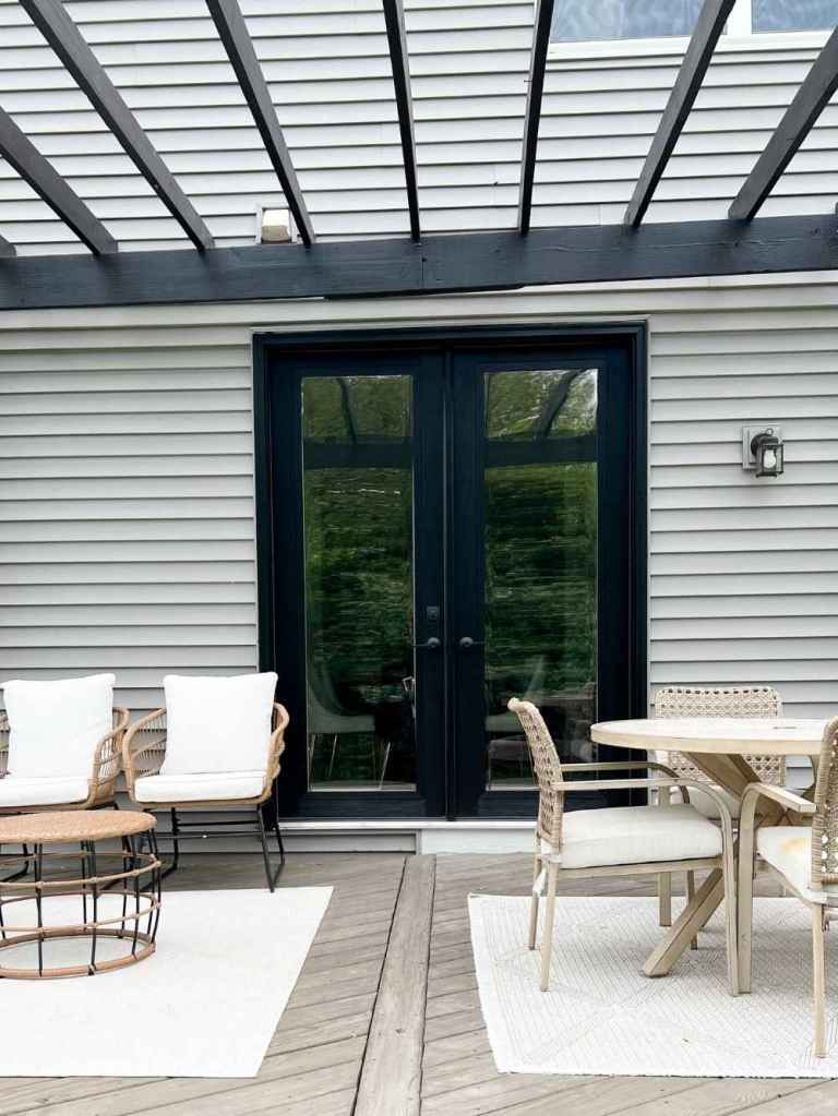 Black double french patio doors installed by Universal Windows Direct lead to a patio underneath a pergola.