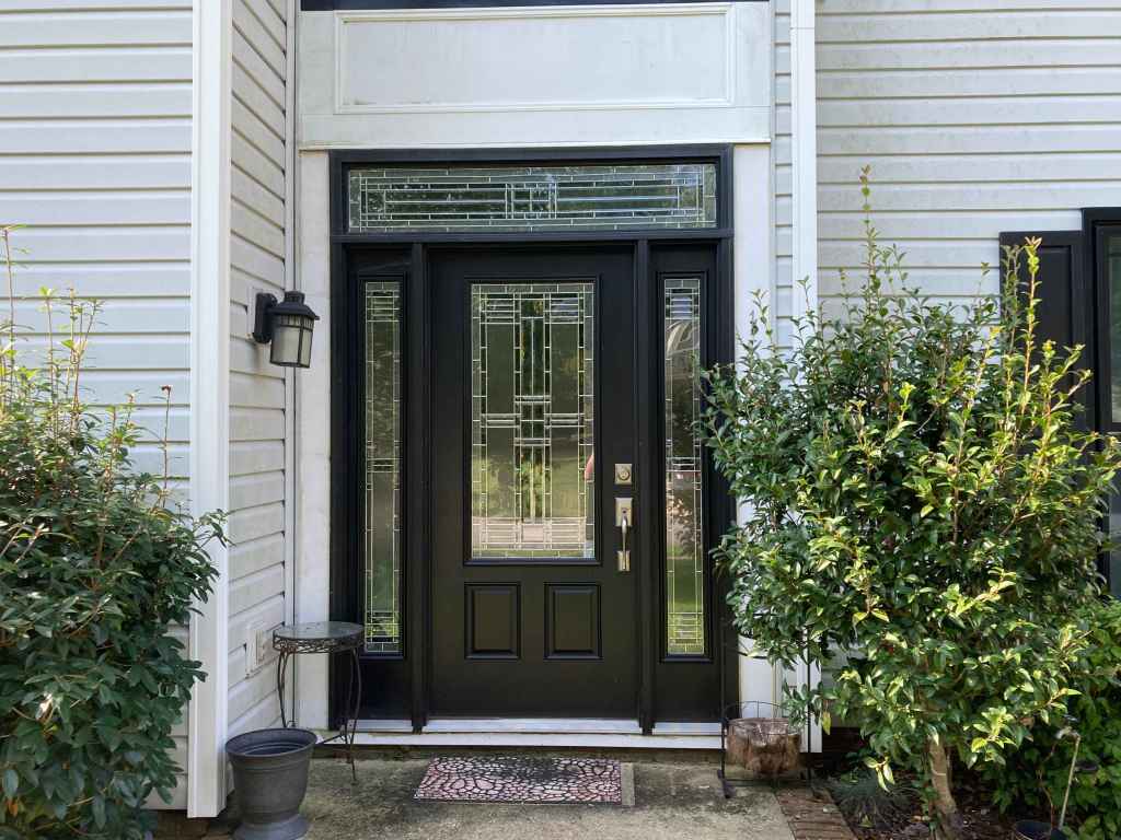 A black front door with decorative glass above, next to and within it installed by Universal Windows Direct.