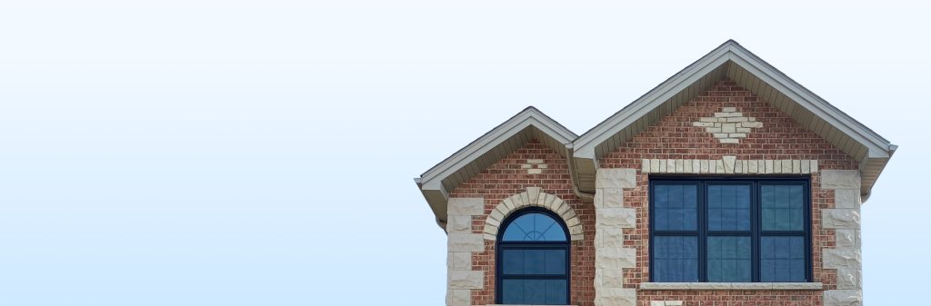 A brick house with black frame windows stands in front of a clear blue sky.