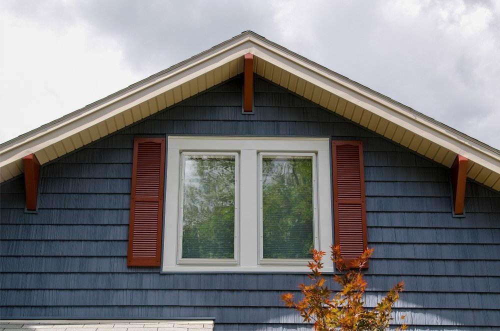 A house with blue shakes siding and red shutters and red gables. Siding and window installed by Universal Windows Direct.
