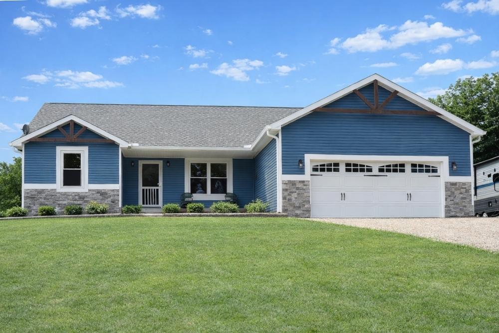 A house with stone accents and blue horizontal siding installed by Universal Windows Direct.