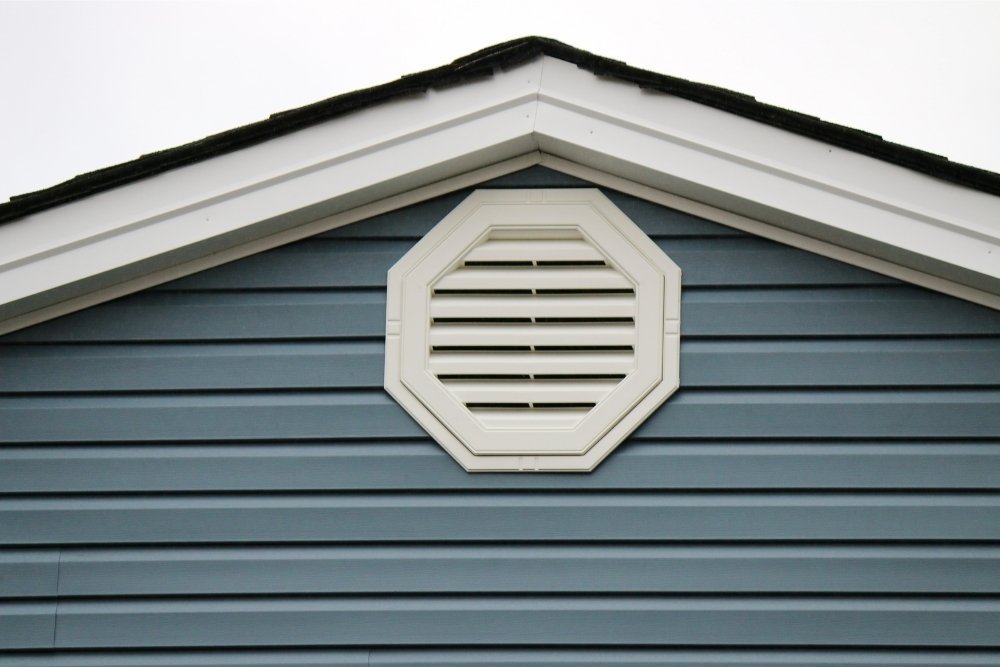 A close up of an attic vent on a house with blue siding installed by Universal Windows Direct.