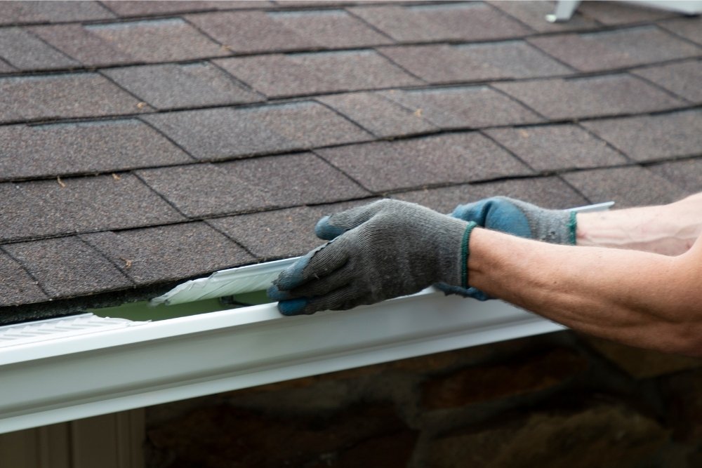 An expert from Universal Windows Direct installs a gutter guard on a gutter.