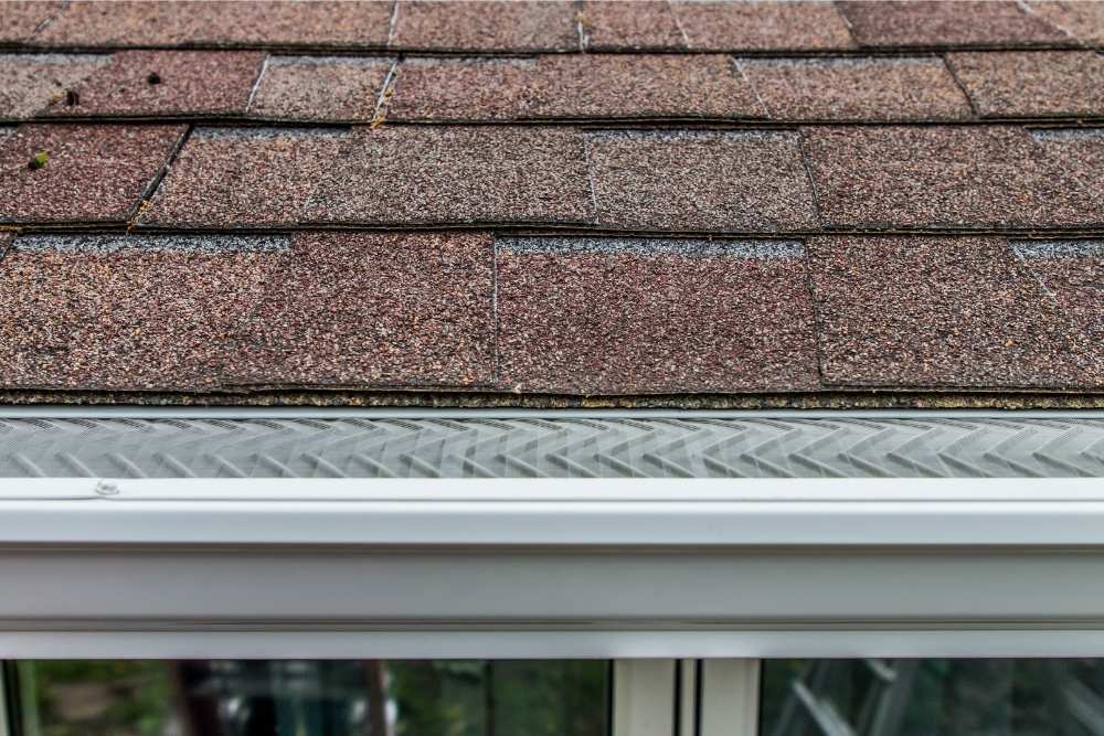 A gutter with a gutter guard installed by Universal Windows Direct at a roof's edge.