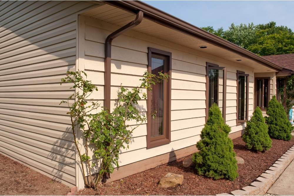 A house with a brown gutter system and cream siding installed by Universal Windows Direct.