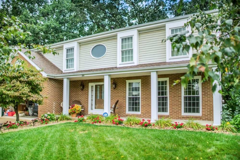 A house with brick on the bottom and cream horizontal sizing at the top installed by Universal Windows Direct.