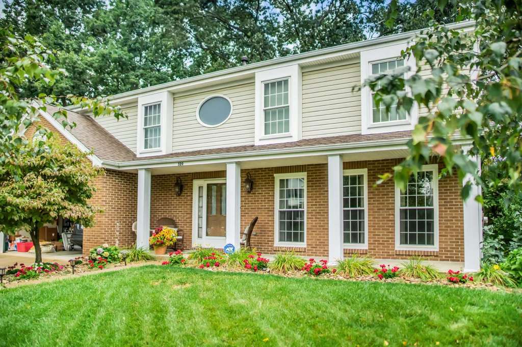 Two-story home with white grid replacement windows and a covered front porch
