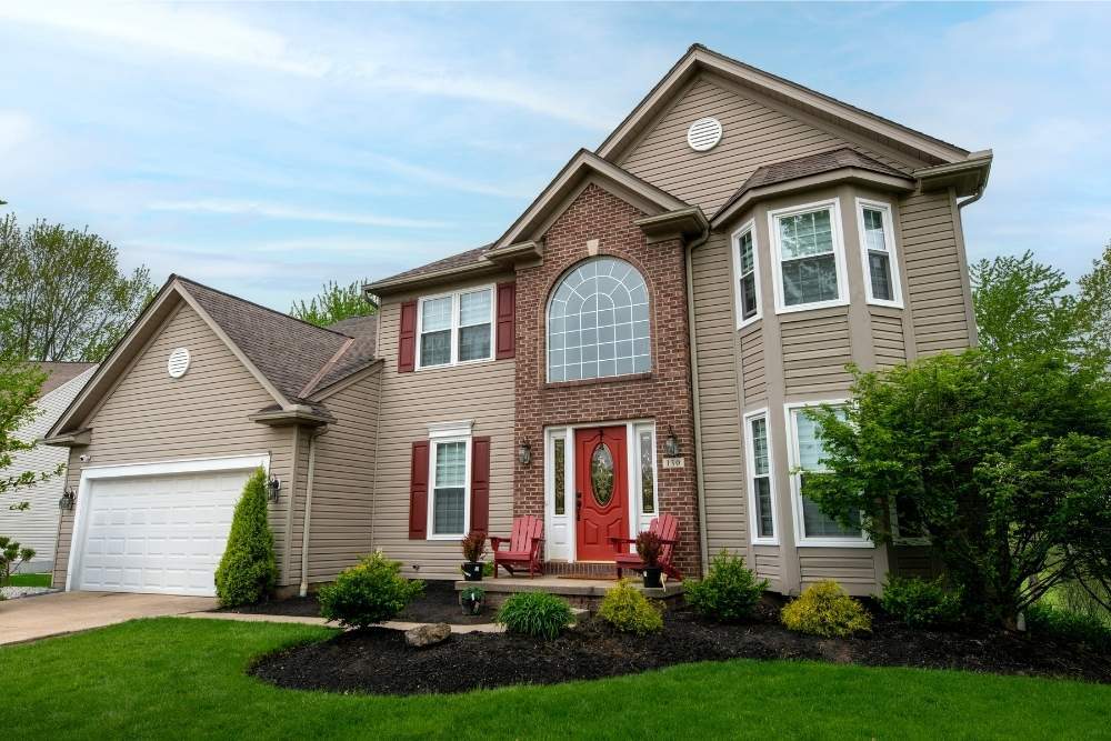 Front view of a house with a uniquely shaped grided window installed by Universal Windows Direct above a bright red front door.