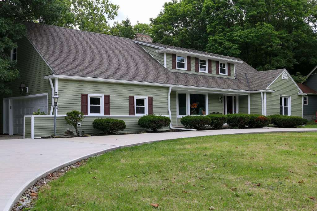 Green vinyl siding on a two-story home with burgundy shutters