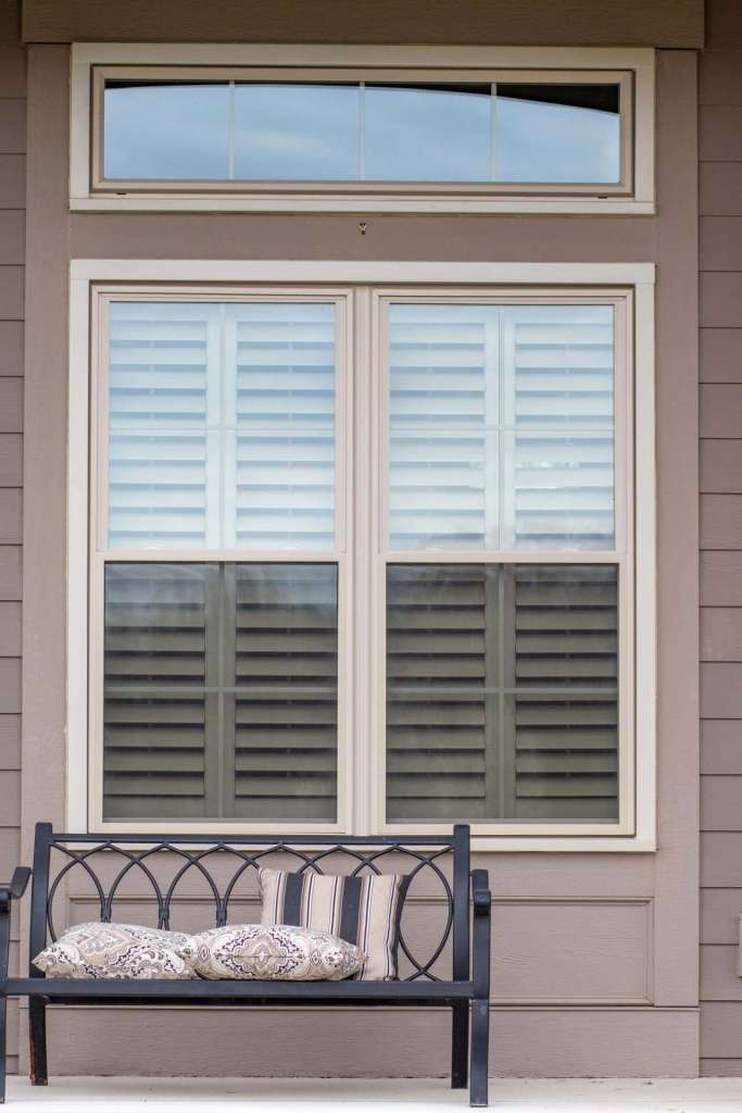 Twin double-hung windows with a transom above, seen from a covered porch