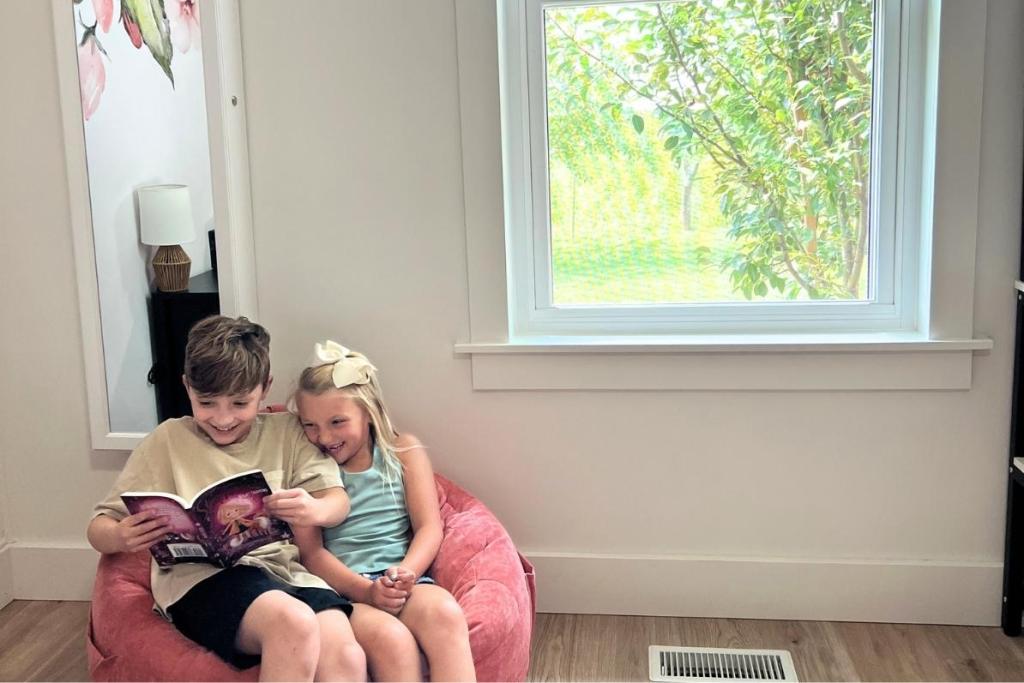 Two young kids happily read in front of a newly replace window by Universal Windows Direct.