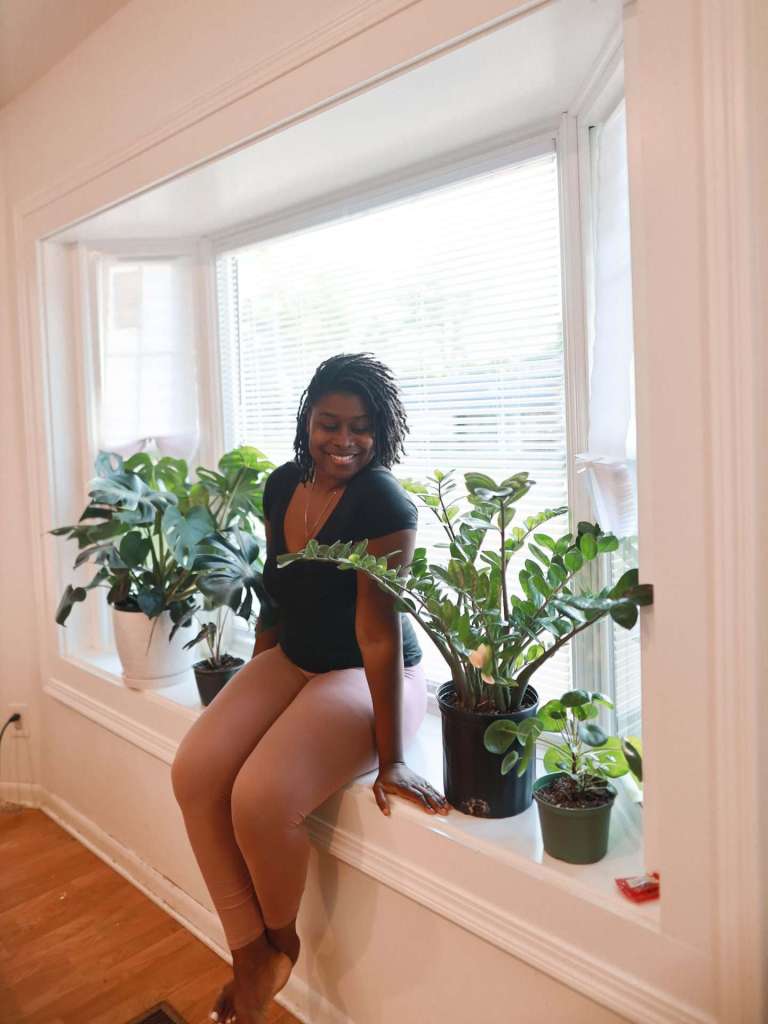 Homeowner sitting in a bright bay window filled with houseplants