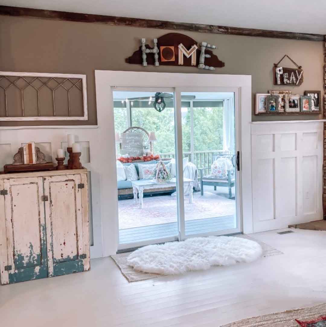 Sliding patio door in a farmhouse living room opening onto a covered porch with outdoor seating