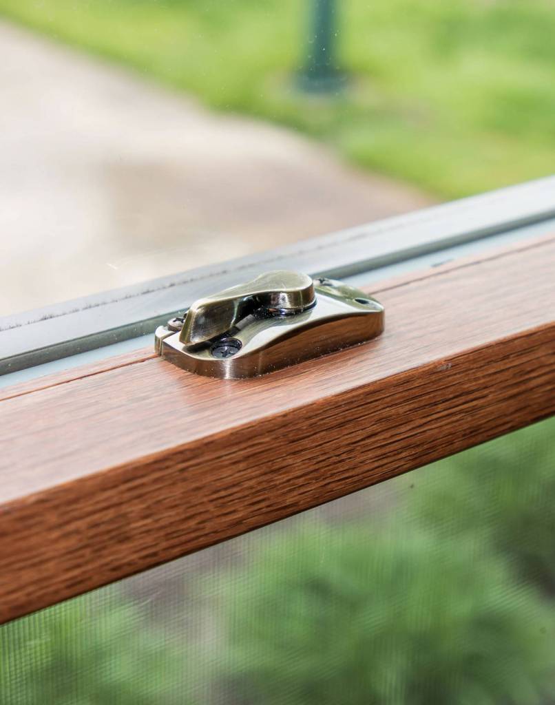 Close-up of a sash lock on a wood-grain window frame