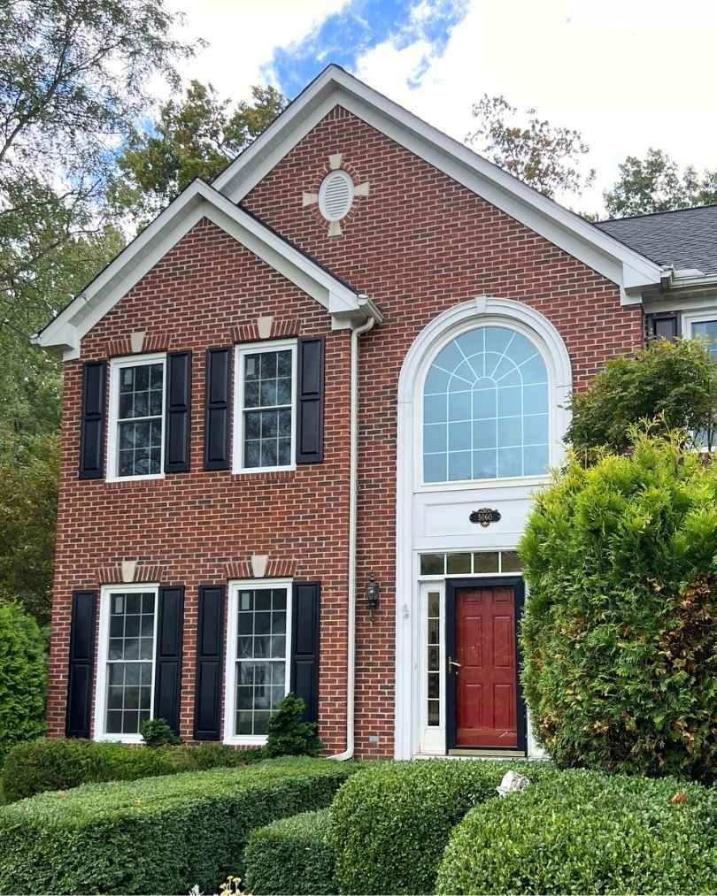 Red brick house with window and front door replacement by Universal Windows Direct.