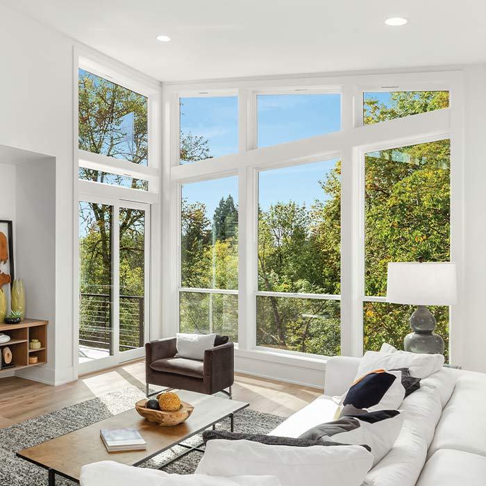 Sunlit living room walled with white replacement windows
