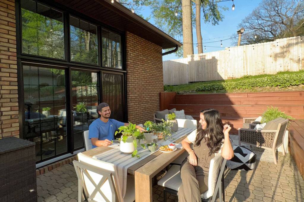 Couple on a patio outside black-framed sliding glass doors