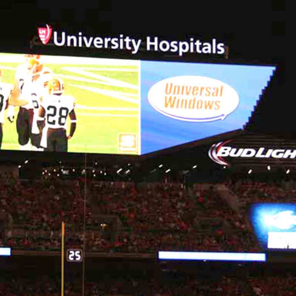 The Cleveland Browns stadium video board showing a Universal Windows Direct ad during a night game
