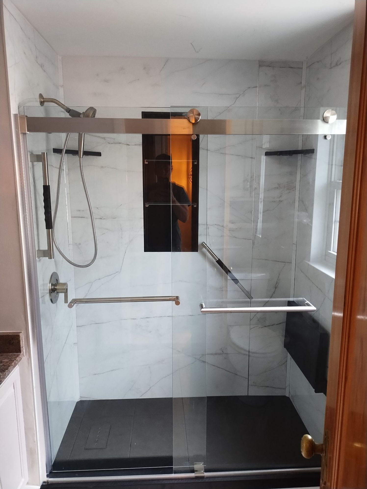 A freshly remodeled bathroom with accessibility features like a fold down seat and grab bar.