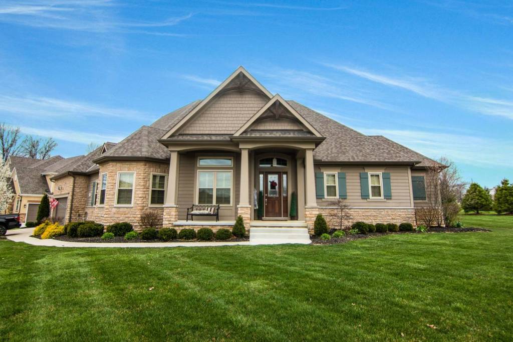Stone and shake craftsman-style home with new white windows and a covered front porch