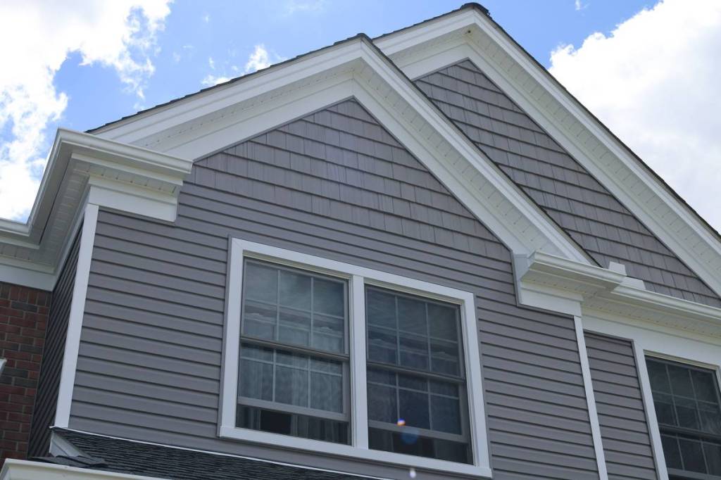 Gray vinyl lap siding and shake gables with white trim on a two-story home